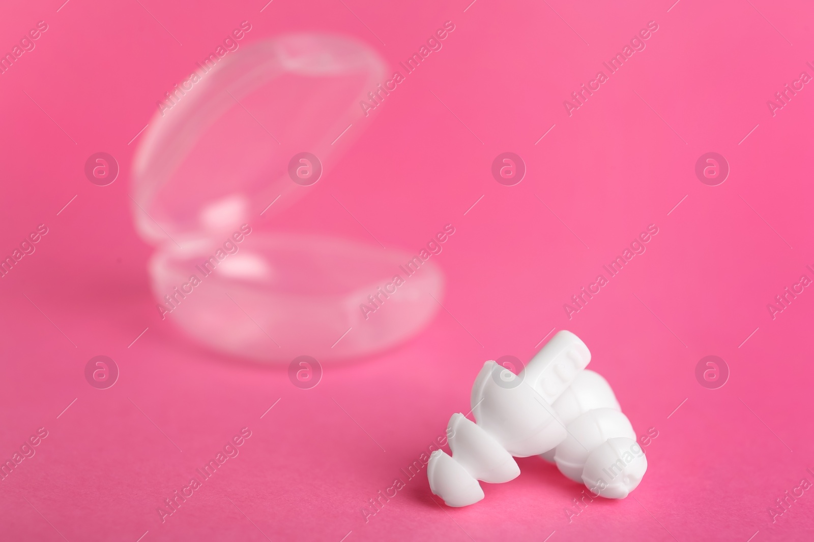 Photo of Pair of white ear plugs on pink background. Space for text