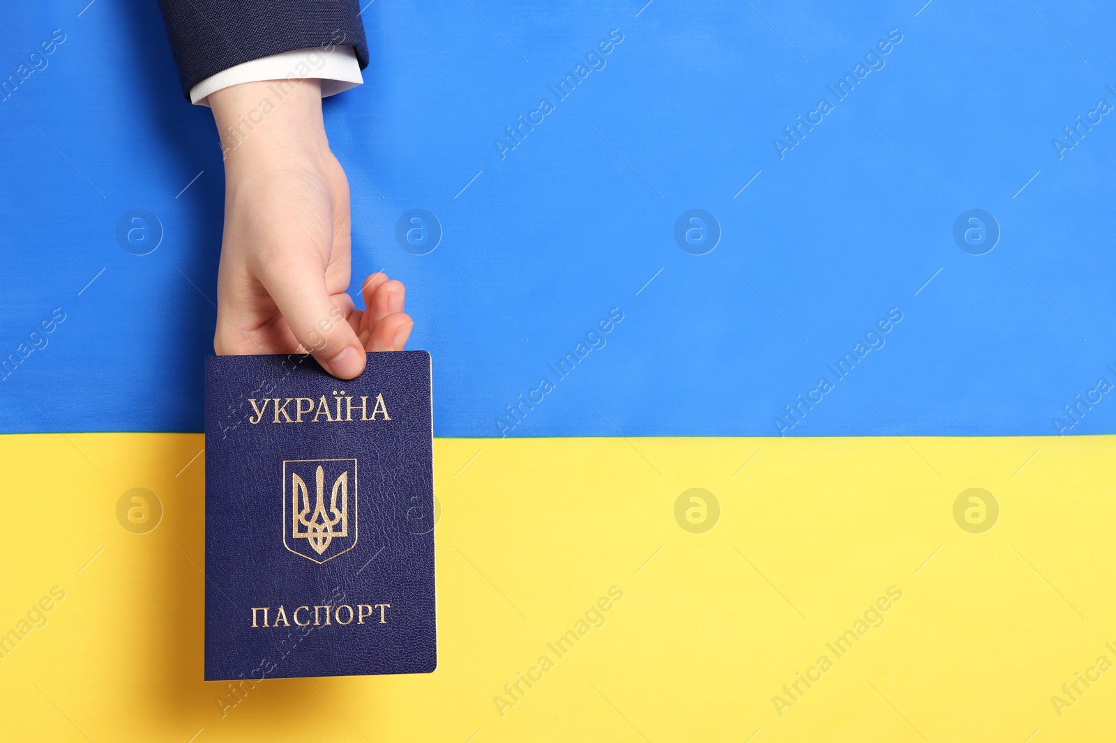 Photo of Woman holding Ukrainian internal passport over national flag, top view. Space for text