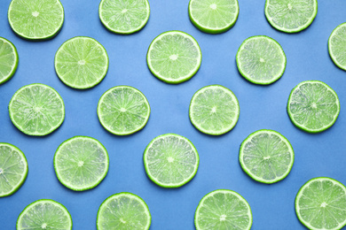 Photo of Juicy fresh lime slices on blue background, flat lay