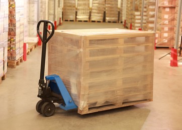 Image of Wooden pallets wrapped in stretch on manual forklift indoors