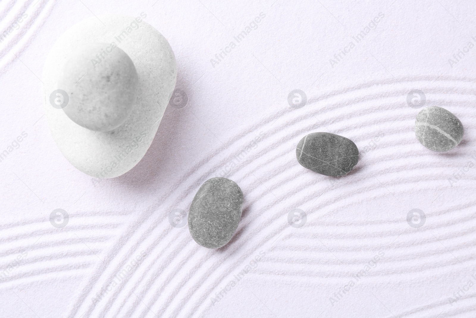 Photo of Zen garden stones on white sand with pattern, flat lay