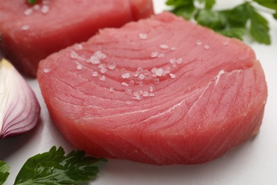 Photo of Raw tuna fillets and spices on white table, closeup