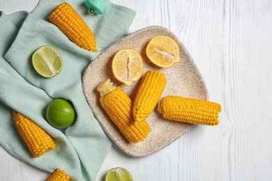 Flat lay composition with corn cobs and citrus fruits on white wooden background