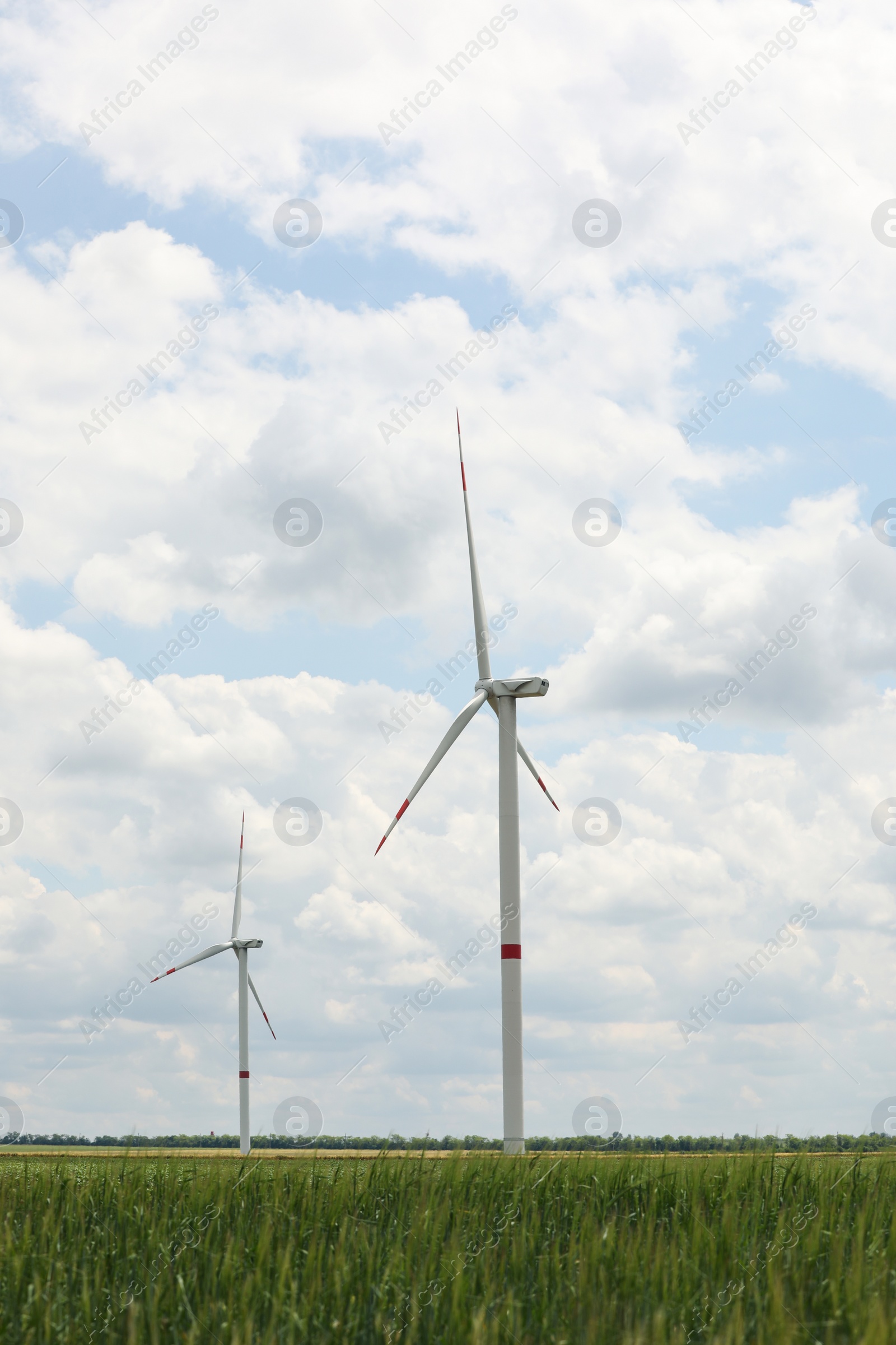 Photo of Modern wind turbines in field on cloudy day. Alternative energy source