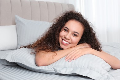 Happy beautiful African American woman lying on bed at home
