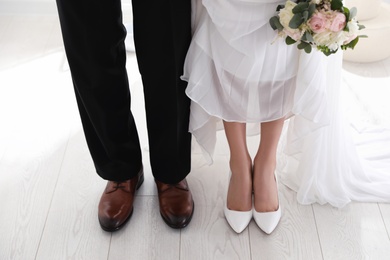 Photo of Bride and groom wearing elegant classic wedding shoes indoors, closeup