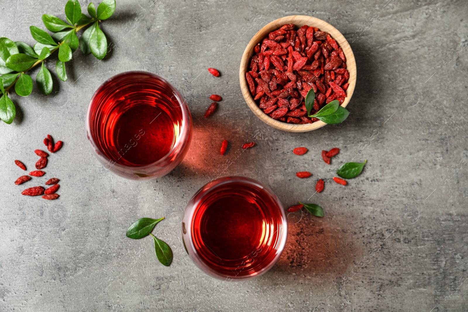 Photo of Flat lay composition with glasses of healthy goji juice on grey table