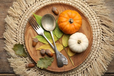 Seasonal table setting with pumpkins and other autumn decor on wooden background, flat lay