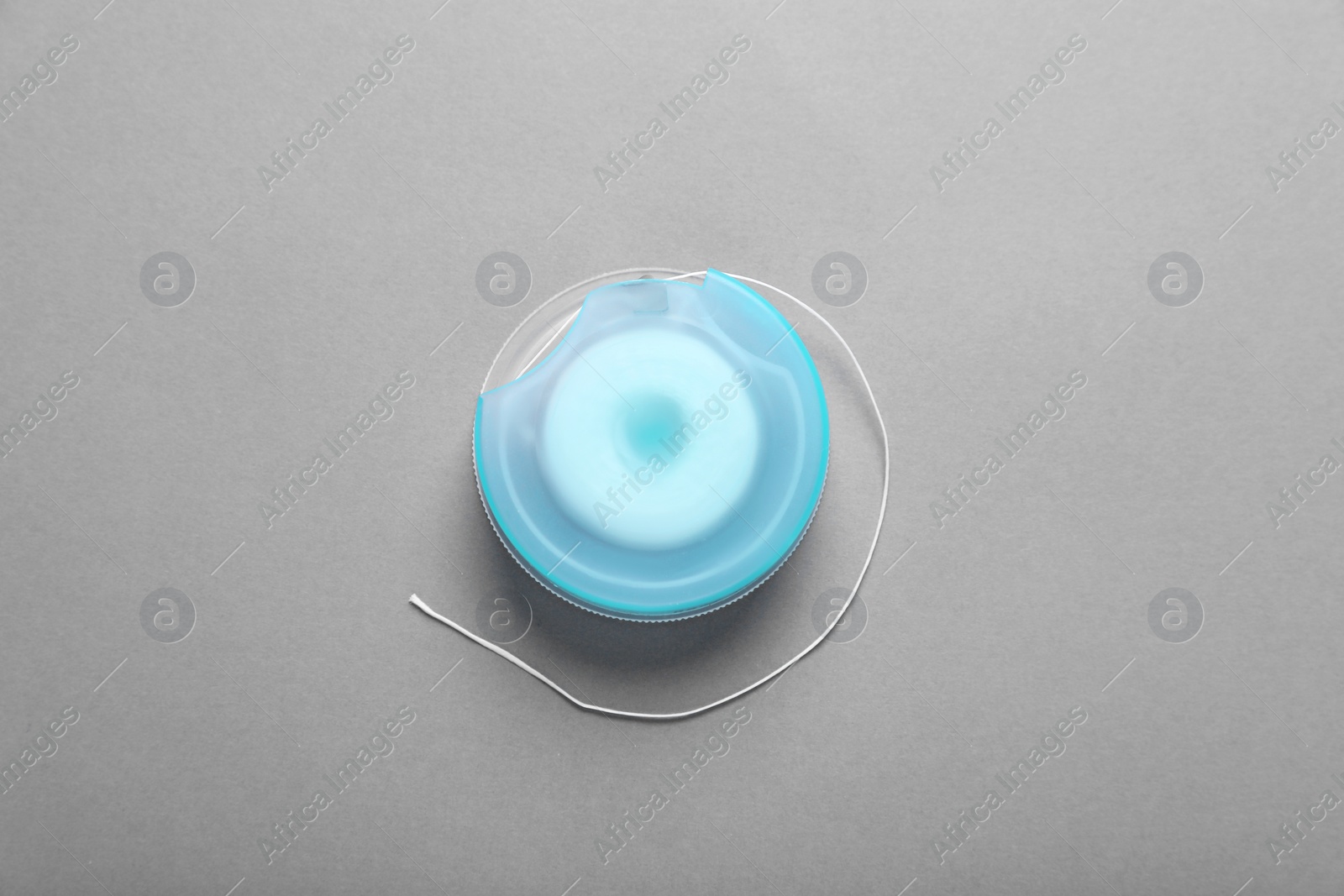 Photo of Container with dental floss on grey background, top view