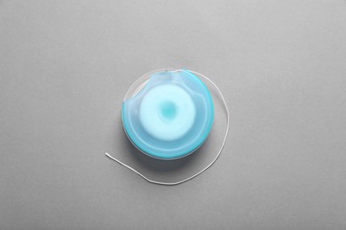 Container with dental floss on grey background, top view