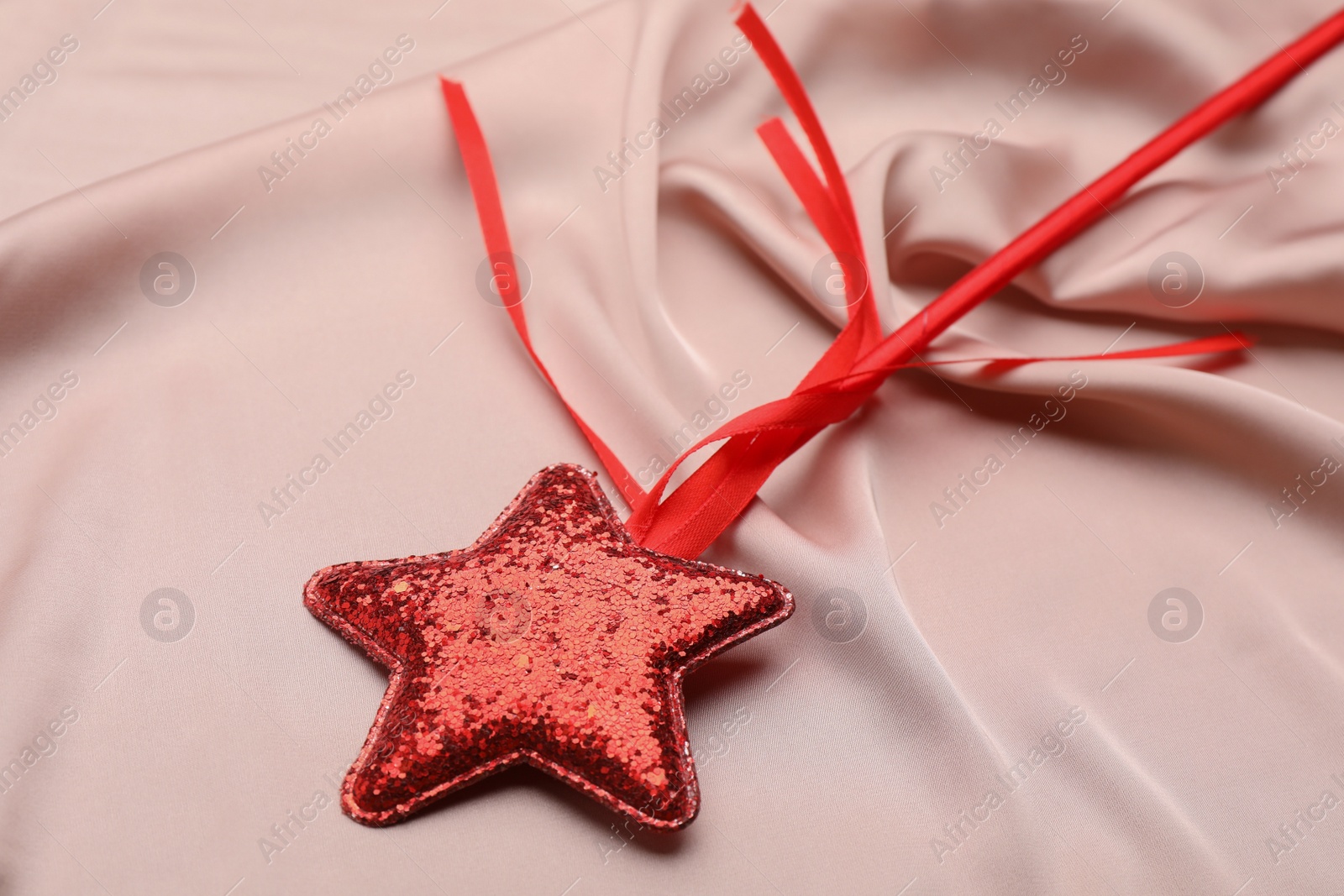 Photo of Beautiful red magic wand on pink fabric