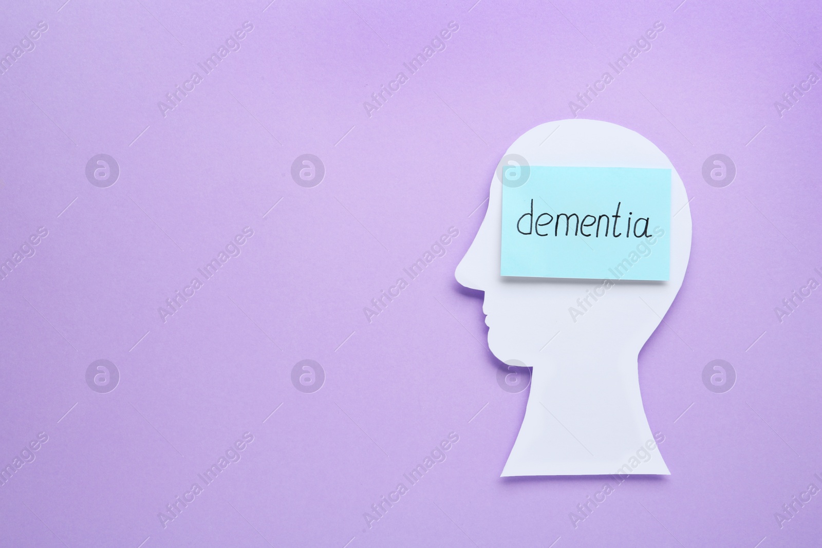 Photo of Human head cutout and note with word Dementia on violet background, top view. Space for text