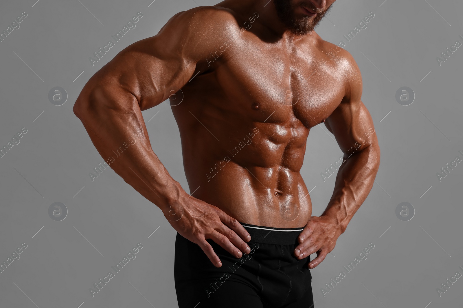 Photo of Young bodybuilder with muscular body on grey background, closeup