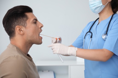 Photo of Doctor taking sample for DNA test from man in clinic