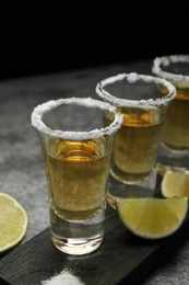 Photo of Mexican Tequila shots, lime slices and salt on grey table