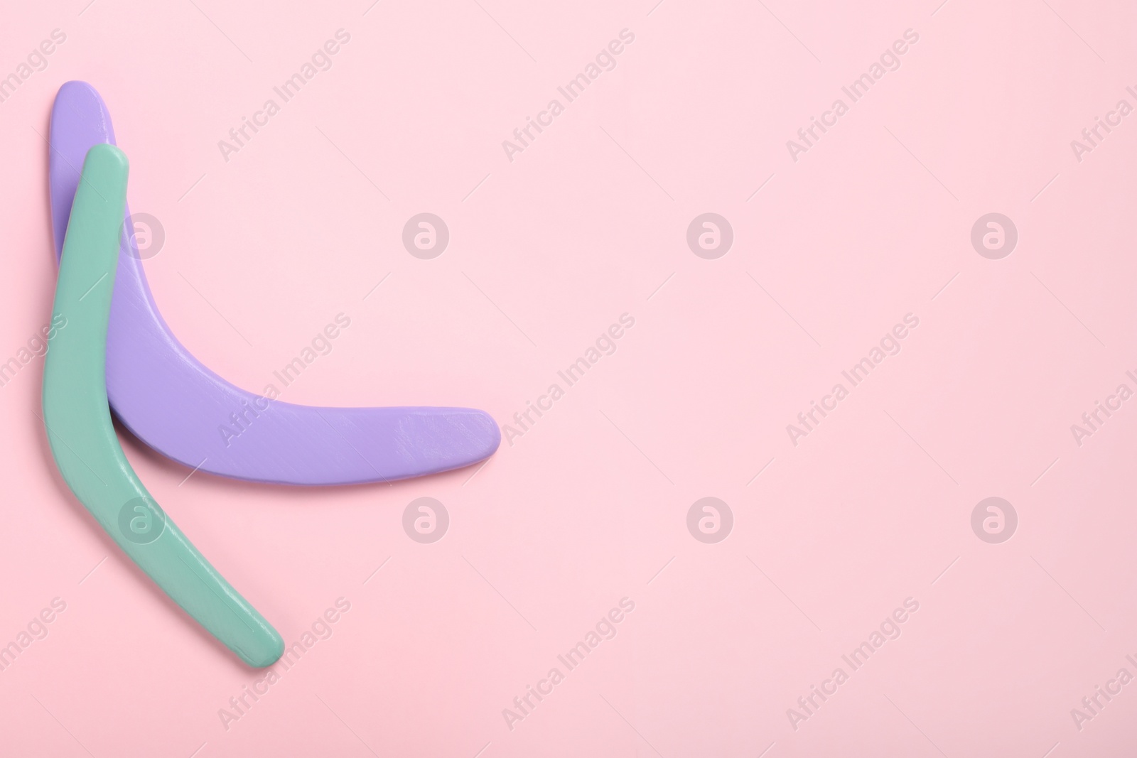 Photo of Colorful wooden boomerangs on pink background, flat lay. Space for text