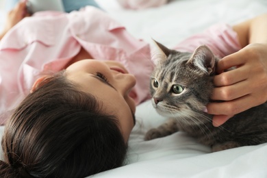 Young woman with cute cat on bed. Pet and owner