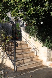 Photo of View of concrete stairs with metal handrails and plants near house outdoors