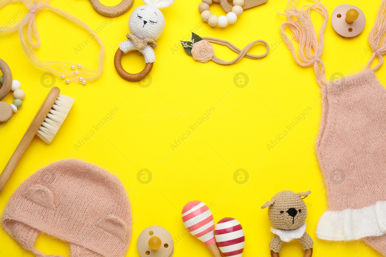 Photo of Frame of baby clothes and accessories on yellow background, flat lay. Space for text