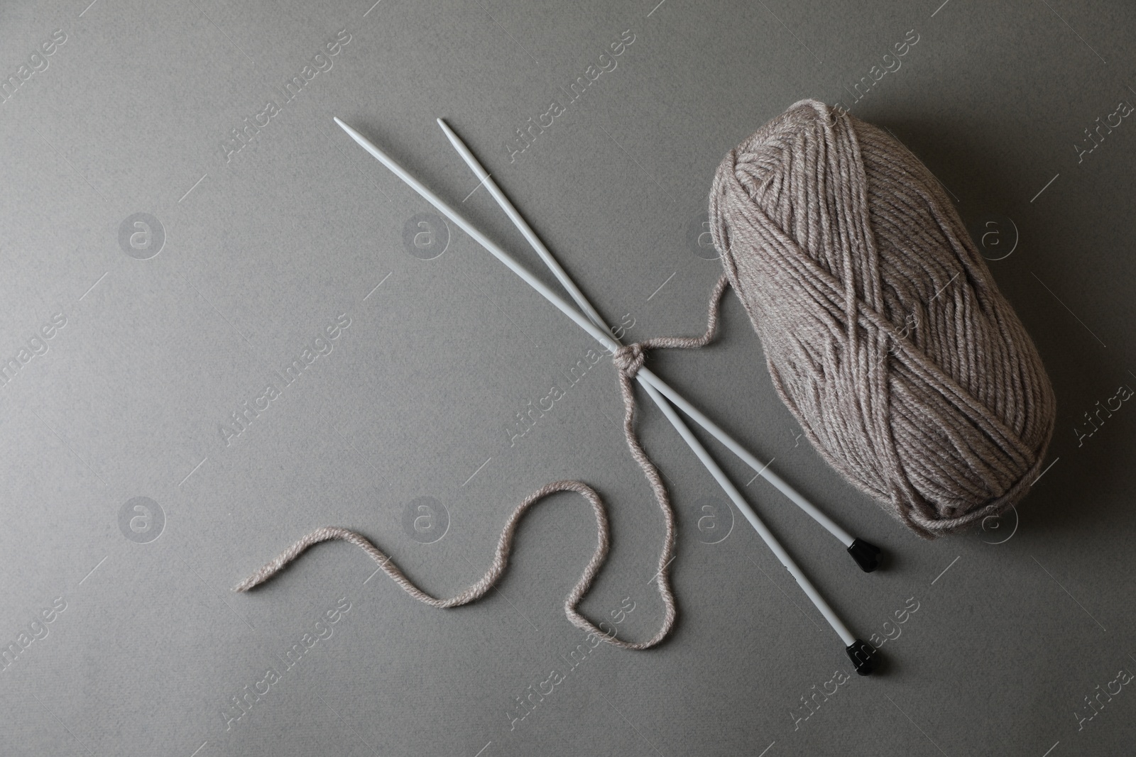 Photo of Soft yarn and knitting needles on light grey background, top view