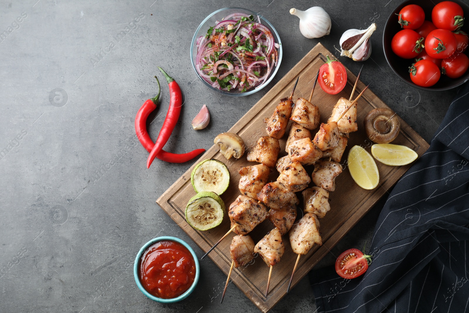 Photo of Delicious shish kebabs with sauce served on grey table, flat lay. Space for text