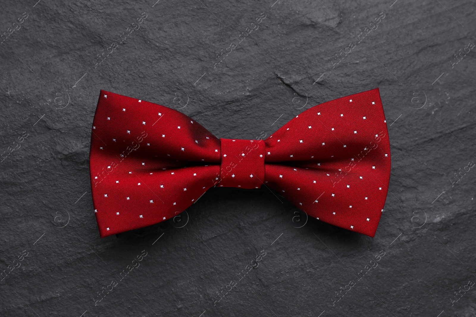 Photo of Stylish burgundy bow tie with polka dot pattern on black table, top view