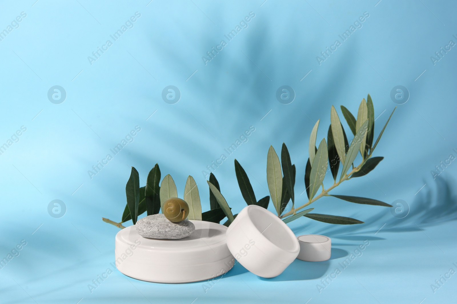 Photo of Jars of olive cream on light blue background. Cosmetic products