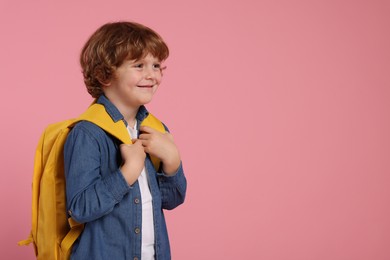 Happy schoolboy with backpack on pink background, space for text