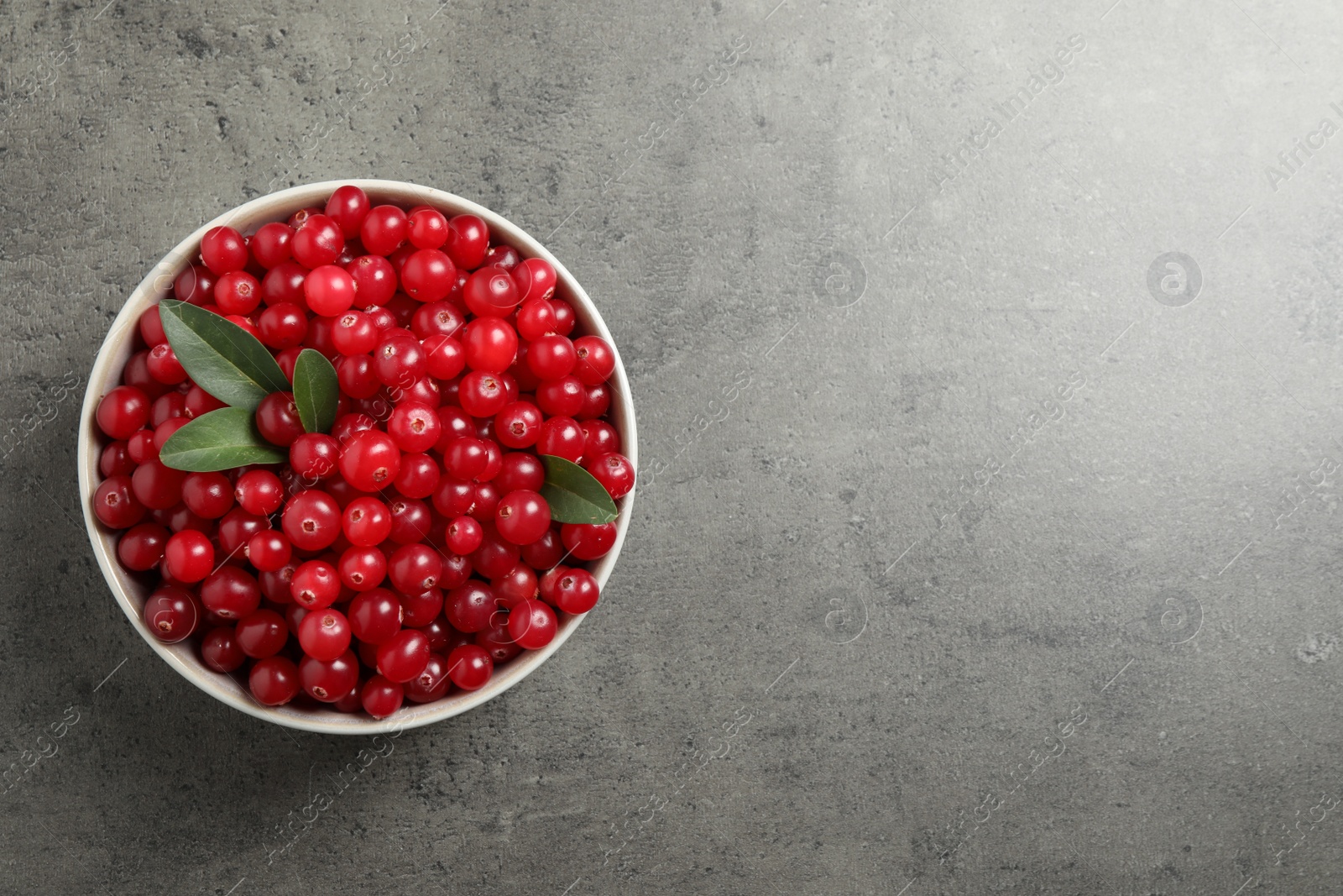 Photo of Ripe fresh cranberry on grey table, top view. Space for text