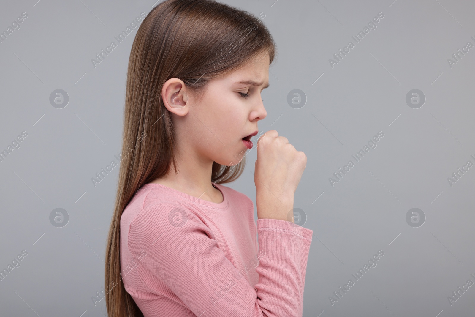 Photo of Sick girl coughing on gray background, space for text