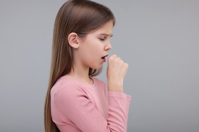 Sick girl coughing on gray background, space for text