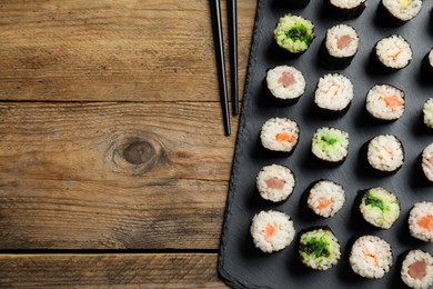 Tasty sushi rolls served on wooden table, flat lay. Space for text