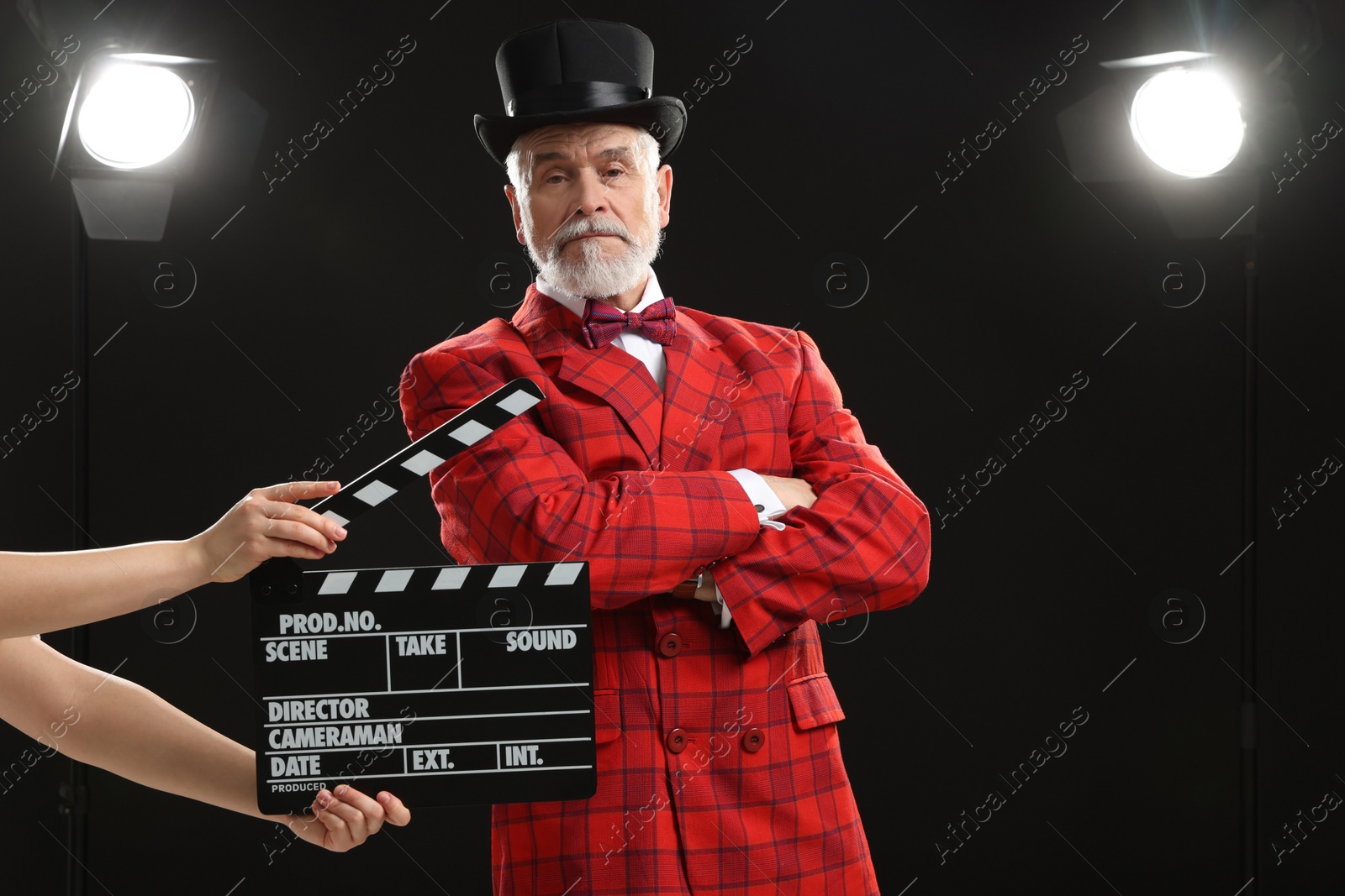 Photo of Senior actor performing role while second assistant camera holding clapperboard on stage. Film industry