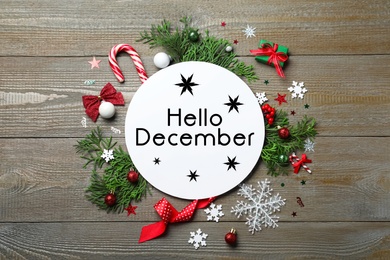 Image of Greeting card with text Hello December, fir tree branches and Christmas decor on wooden background, flat lay