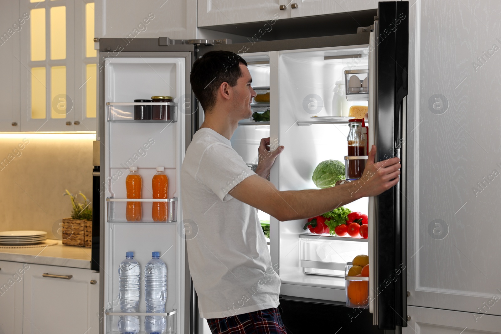 Photo of Happy man near refrigerator in kitchen at home