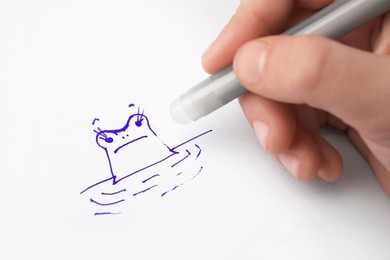 Photo of Child erasing drawing with erasable pen on paper sheet, closeup