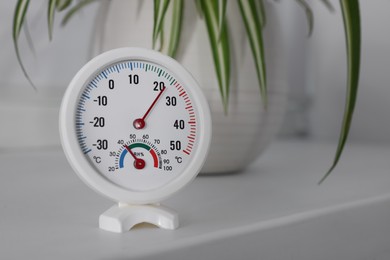 Photo of Round mechanical hygrometer on white table indoors. Space for text