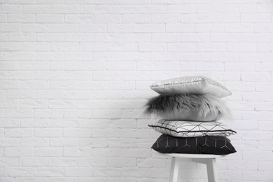 Photo of Many different pillows on chair near brick wall with space for text