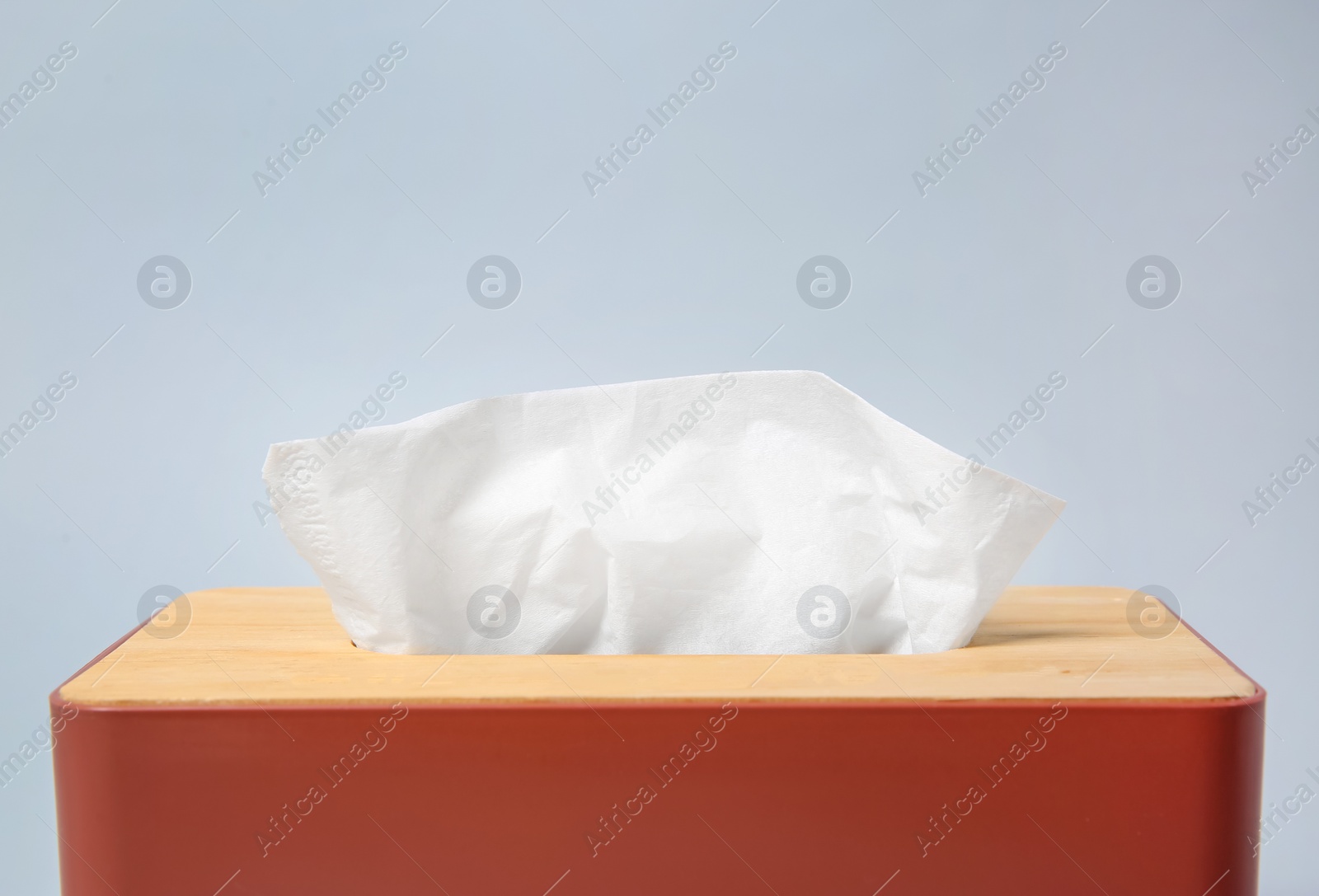 Photo of Holder with paper tissues on light grey background, closeup