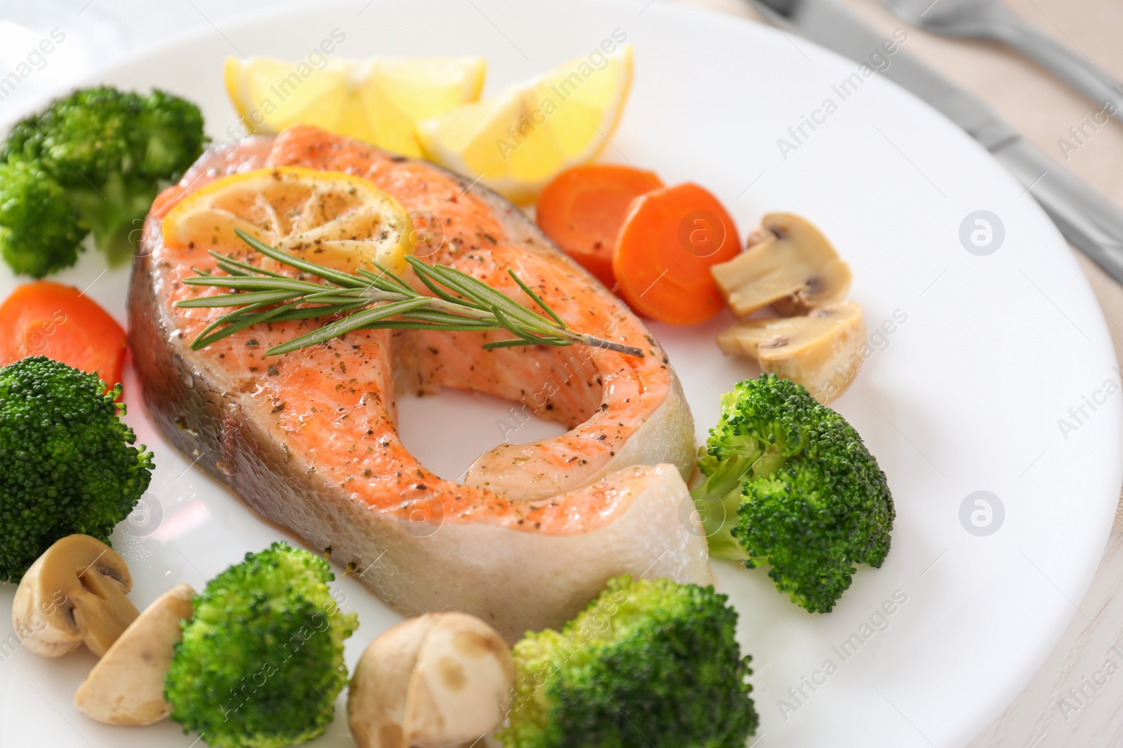 Photo of Plate with salmon steak and garnish prepared in multi cooker on table, closeup