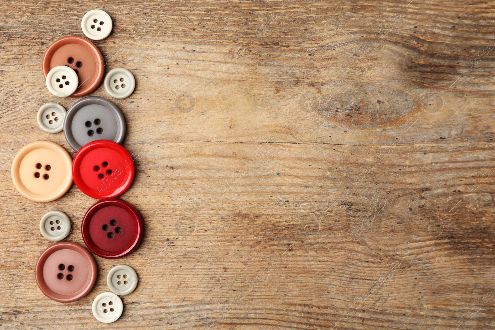 Photo of Many plastic sewing buttons on wooden background, flat lay. Space for text