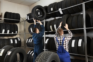 Photo of Young male mechanics with car tires in automobile service center