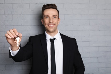 Photo of Male real estate agent with key on brick wall background