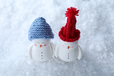 Photo of Cute decorative snowmen in color hats on artificial snow