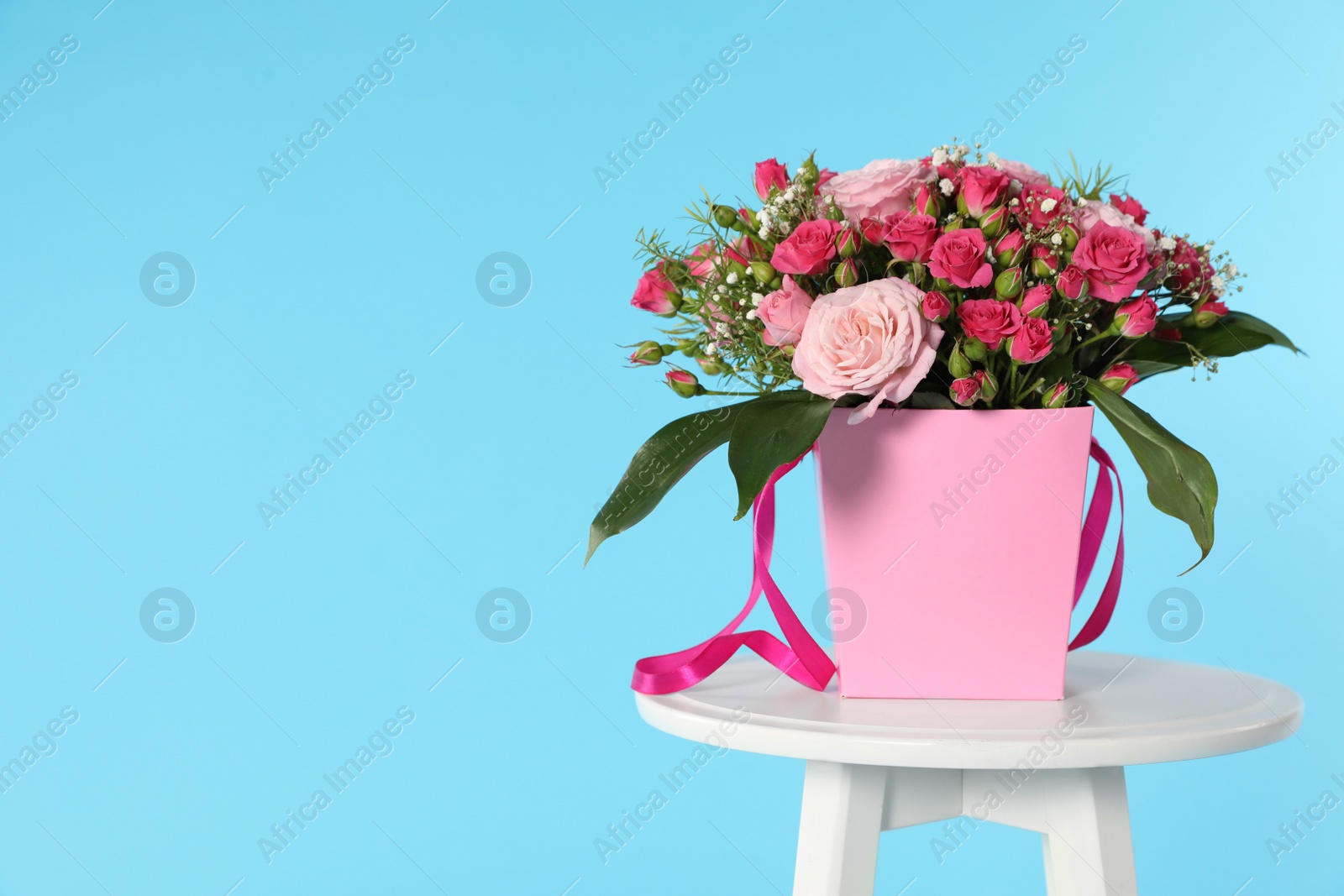 Photo of Beautiful bouquet of flowers in paper gift box on table against color background. Space for text