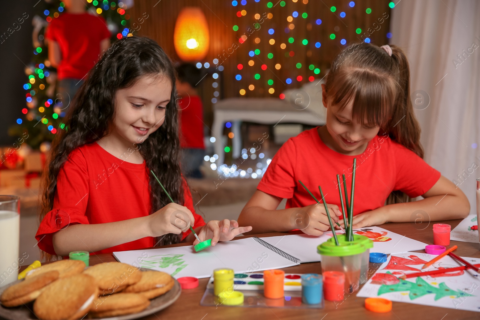 Photo of Little children painting pictures at home. Christmas celebration