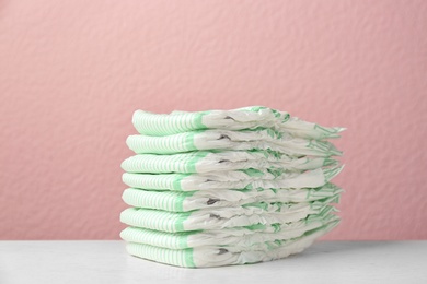 Photo of Stack of diapers on table against color background. Baby accessories