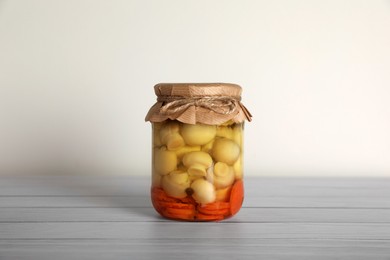 Photo of Jar with pickled mushrooms and carrots on white wooden table