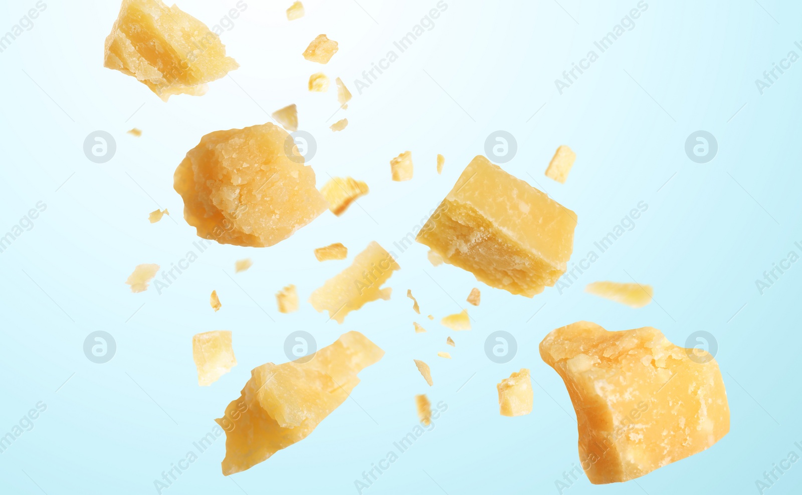 Image of Pieces of delicious parmesan cheese flying on light background