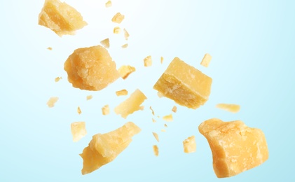 Image of Pieces of delicious parmesan cheese flying on light background